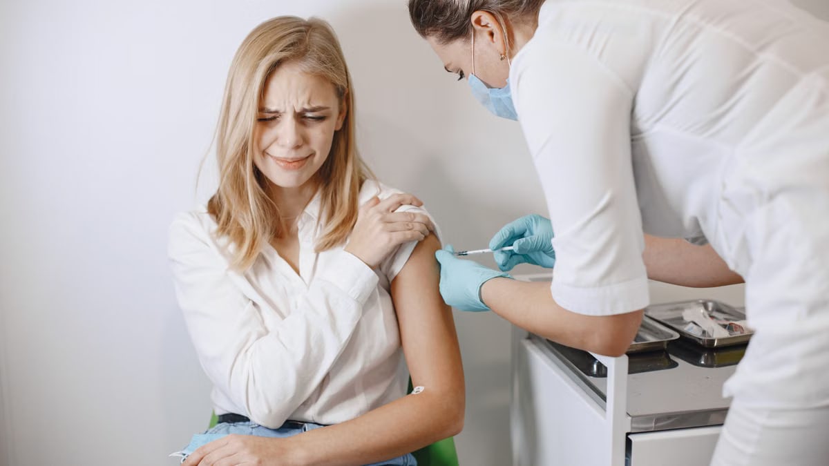 A healthcare professional administers a vaccine to a woman in a clinic setting.